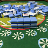 Blue and white striped acrylic Mahjong tiles stacked on a green pinwheel-patterned game mat