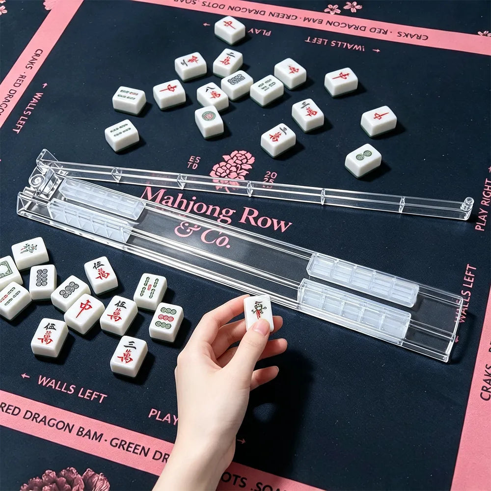 Clear foldable Mahjong tile racks arranged on a black and pink Mahjong mat