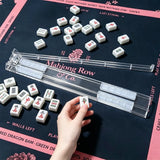 Clear foldable Mahjong tile racks arranged on a black and pink Mahjong mat