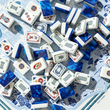 Blue marbled acrylic Mahjong tiles scattered among hand-illustrated bamboo, character and joker tiles on a chinoiserie scorecard mat