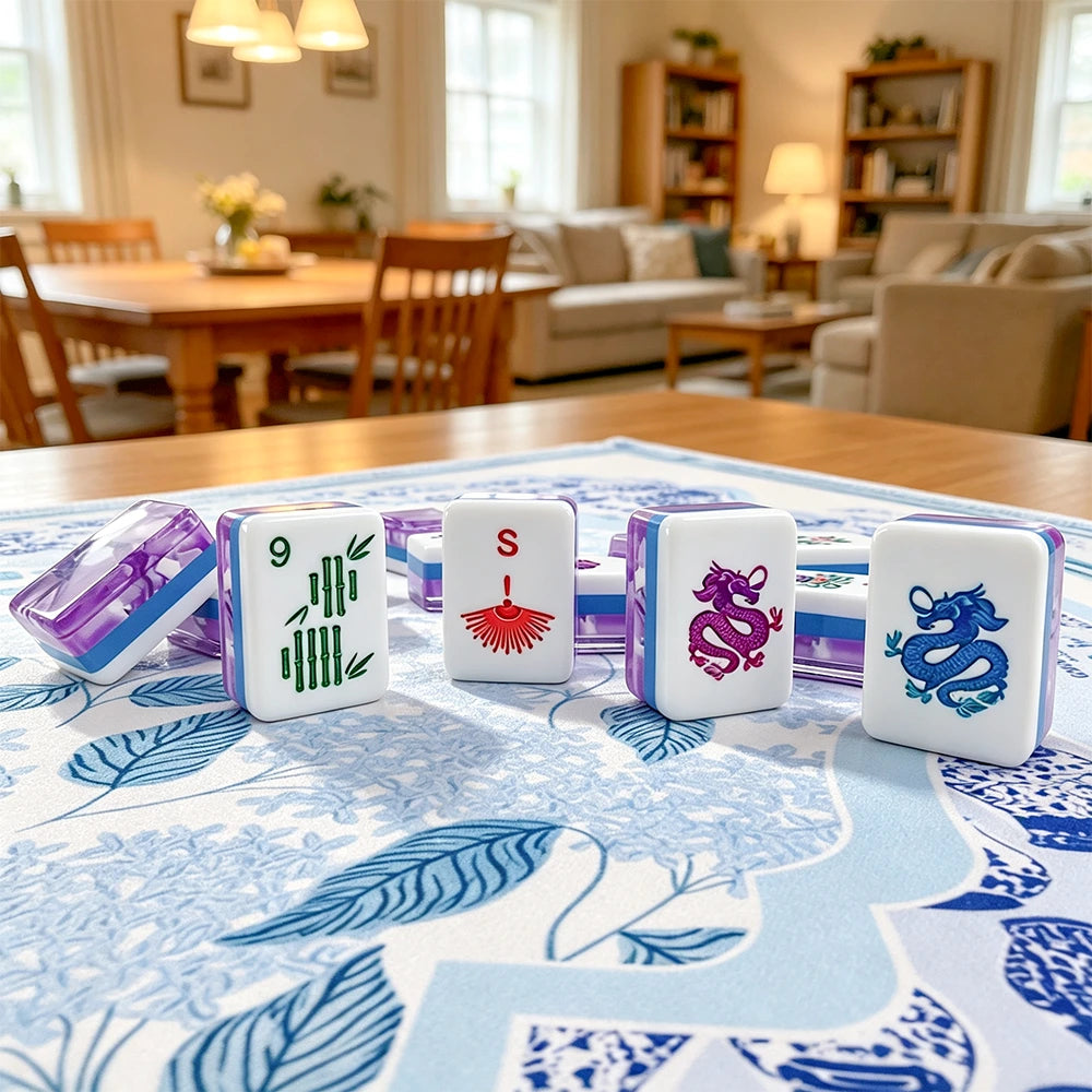 Purple-trimmed acrylic Mahjong tiles with hand-painted bamboo, wind and dragon motifs standing on a blue floral table mat