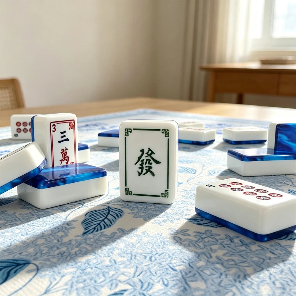 Blue marbled acrylic Mahjong tiles with hand-illustrated character and dot suits resting on a blue floral table mat