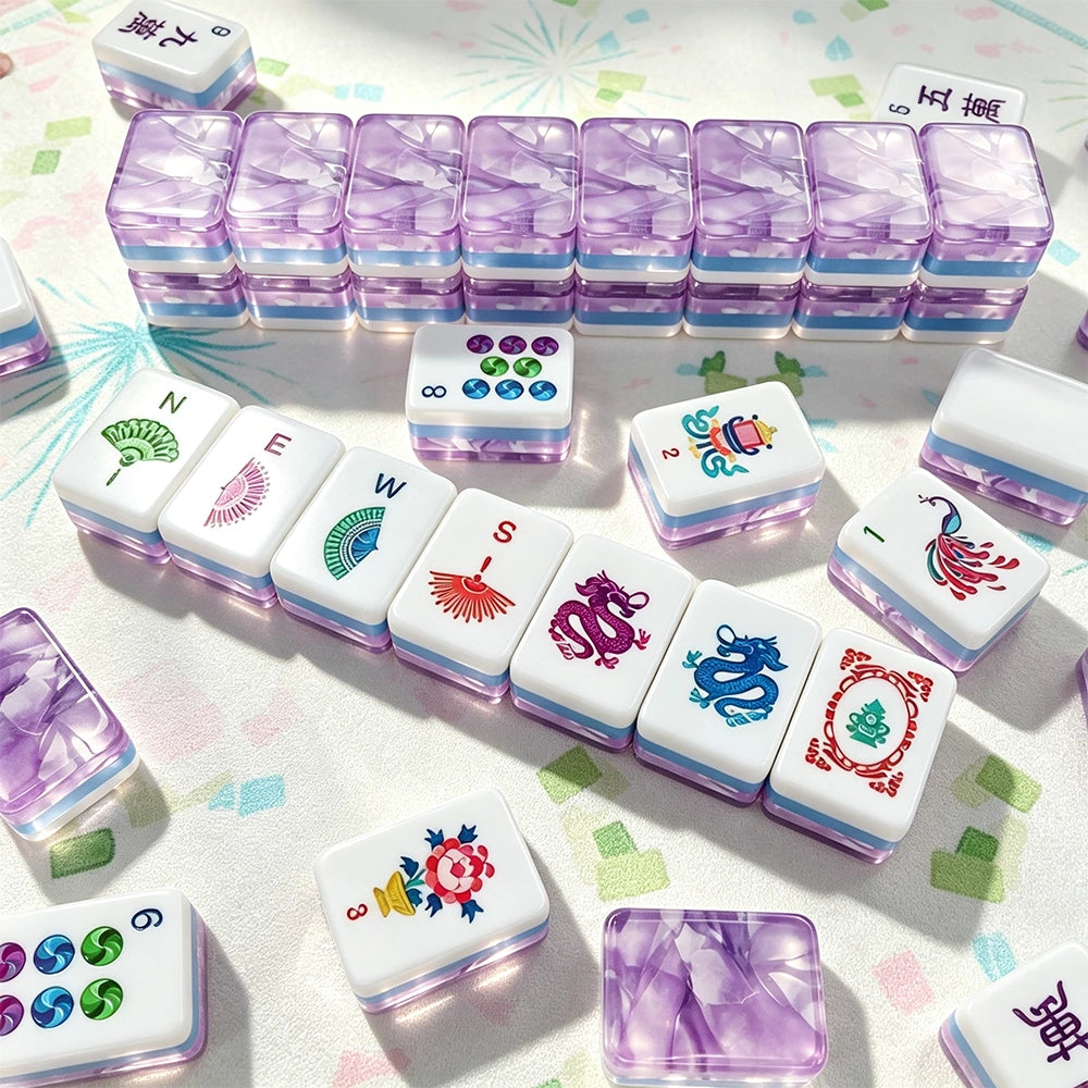 Purple marbled acrylic Mahjong tiles arranged in a wall with hand-illustrated wind, dragon and flower tiles laid out on a patterned mat