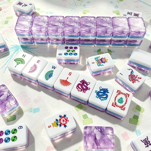 Purple marbled acrylic Mahjong tiles arranged in a wall with hand-illustrated wind, dragon and flower tiles laid out on a patterned mat