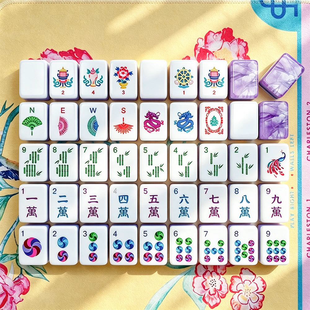 Full layout of hand-illustrated Mahjong tiles including flower, wind, dragon, bamboo, character and dot suits on a floral yellow mat with a purple marbled acrylic tile