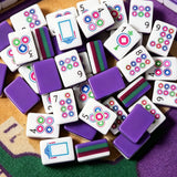 Purple acrylic Mahjong tiles with colourful modern designs arranged on a game table