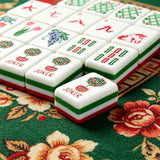 White Mahjong tiles with colourful traditional designs on a red and green game table