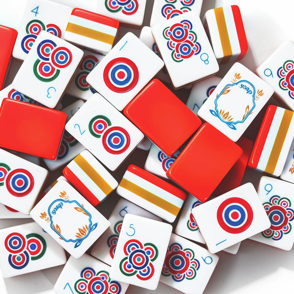 Red acrylic Mahjong tiles with colourful patterns arranged on a game table