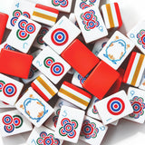Red acrylic Mahjong tiles with colourful patterns arranged on a game table
