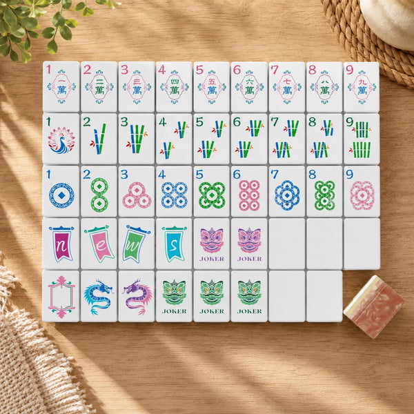 Complete colorful Mahjong tile set with pink marble backs laid out on wood table