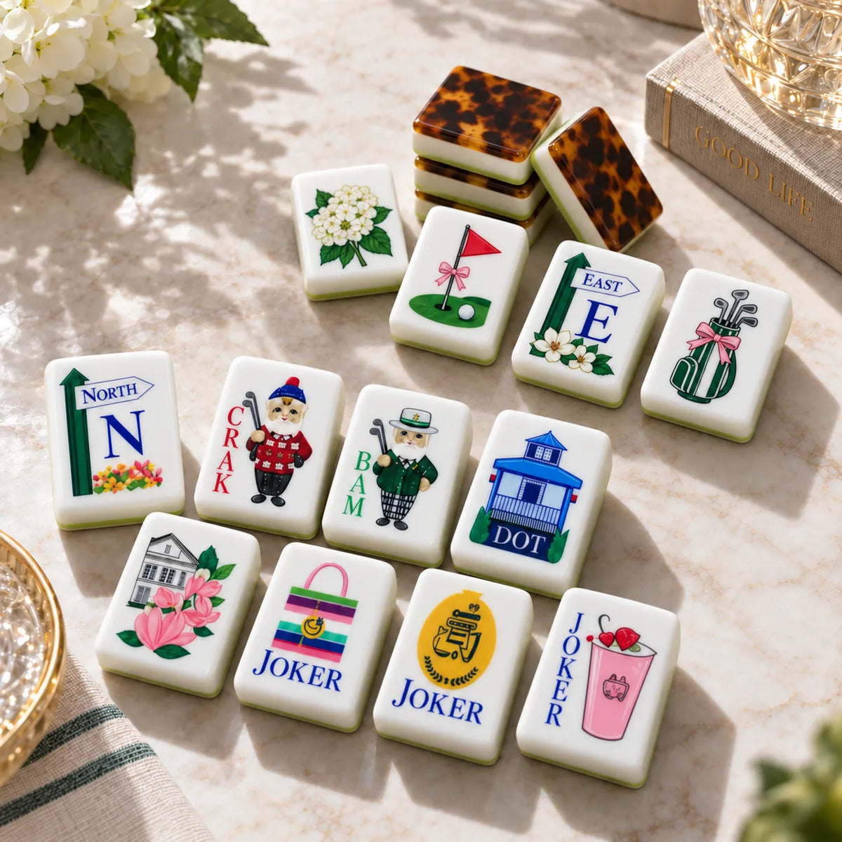 Golf-themed American mahjong tiles with golf flag, golf bag, cat golfer and clubhouse designs and tortoiseshell tile backs on a marble table
