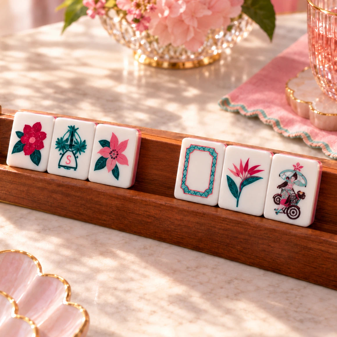 Tropical floral mahjong set in blue acrylic, tiles with flower and wind designs displayed on a wooden rack