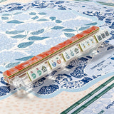 Coral marbled acrylic Mahjong tiles with hand-illustrated wind and joker tiles arranged in a clear tile rack on a blue chinoiserie mat