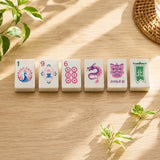 Colorful Mahjong tiles standing in a row on wood table with peacock and dragon designs