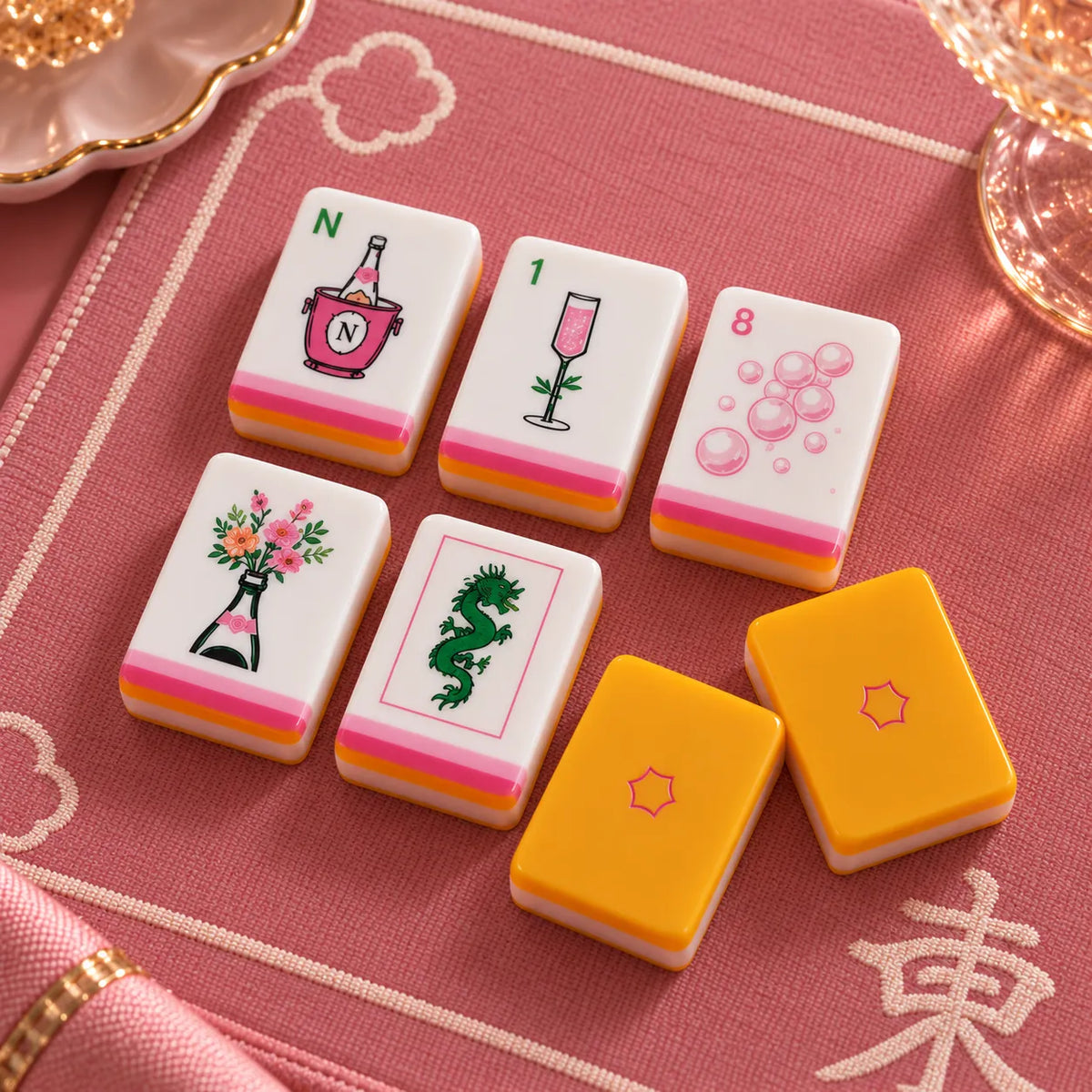 Close view of American mahjong tiles with orange and yellow accents on a red and pink background