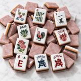 Close view of pink and rose-toned mahjong tiles with illustrated artwork on a table