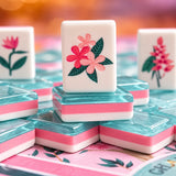 Close-up of a pink plumeria flower mahjong tile on stacked teal and pink three-layer acrylic tiles