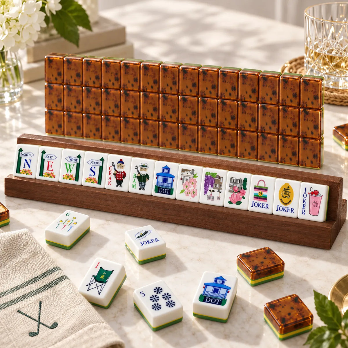 Golf-themed American mahjong tiles on a wooden rack with wind, joker and dot tiles in front of rows of amber tortoiseshell tile backs on a marble table