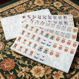 Mother-of-pearl mahjong tile set featuring elegant colourful artwork and a glossy pearl finish displayed on a luxury game table