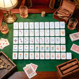 Mother-of-pearl mahjong tile set with elegant colourful artwork arranged on a luxury green game table