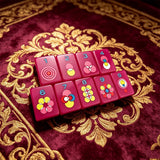 Single-layer neon purple mahjong tile set with colourful designs displayed on an elegant decorative table surface