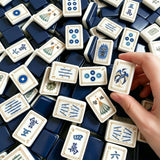 Mahjong tiles displayed with hands arranging the game setup